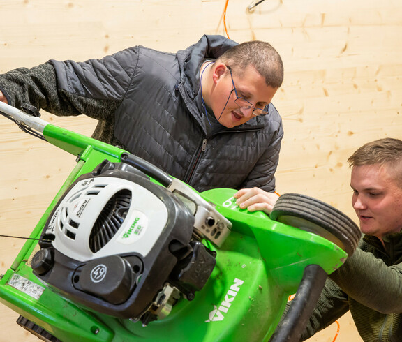 Zwei Männer reparieren einen Rasenmäher