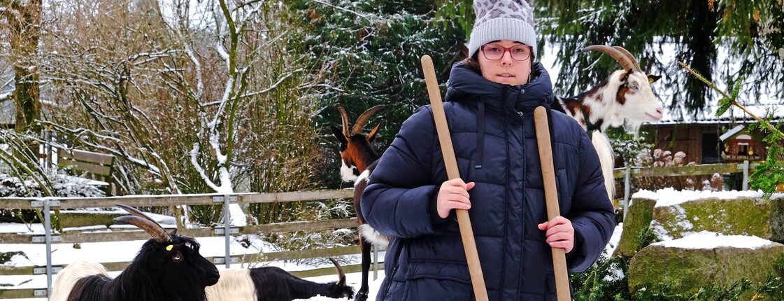 Eine Frau steht in einem Ziegengehege