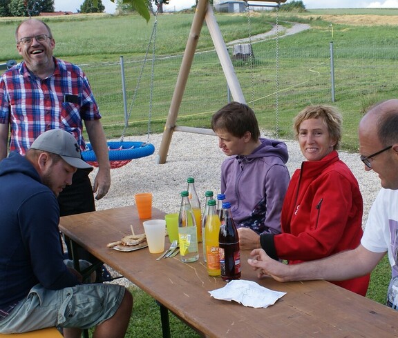 Leute sitzen an einem  Holztisch beim Feiern.