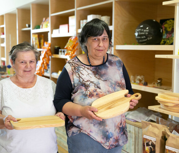 Zwei Frauen halten selbst gemachte Holz-Jausen-Brettl in die Kamera.