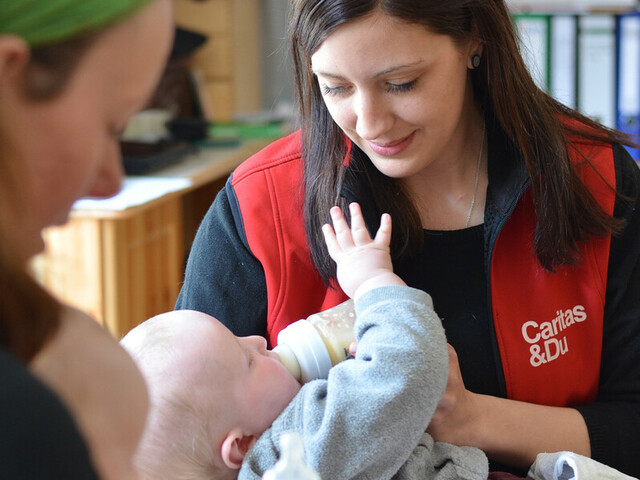 Eine Caritas-Mitarbeiterin füttert ein Baby